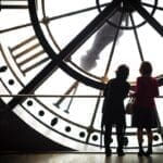 Image of a clock with people standing in front of it