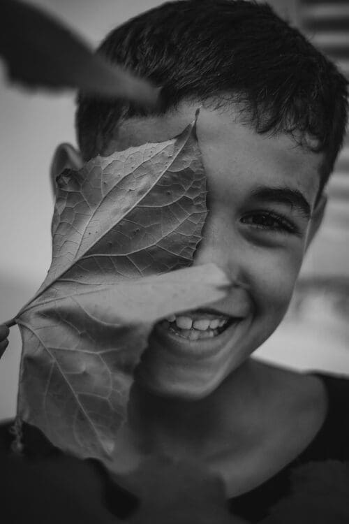 Image of a boy with a leaf in front of his face