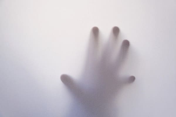 A hand and its fingers touching a window